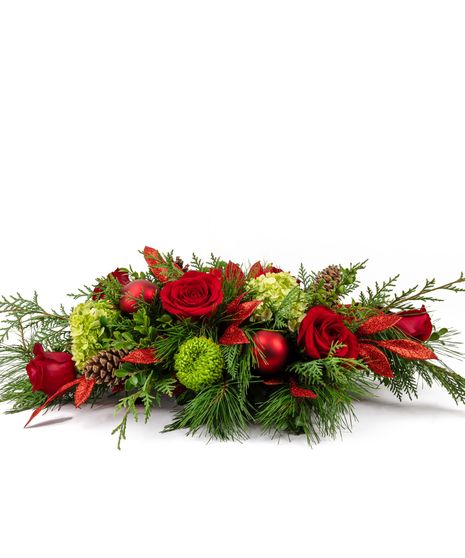 This arrangement, artfully designed in a keepsake basket with red cremones and anemones, white stock, pine cones, and winter greenery help bring playfulness to the holiday. 
