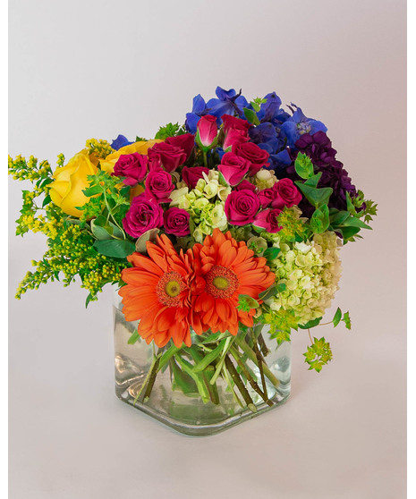 This colorful array of roses, gerbera daisies, delphinium, spray roses and more is sure to bring a smile to anyone's face.