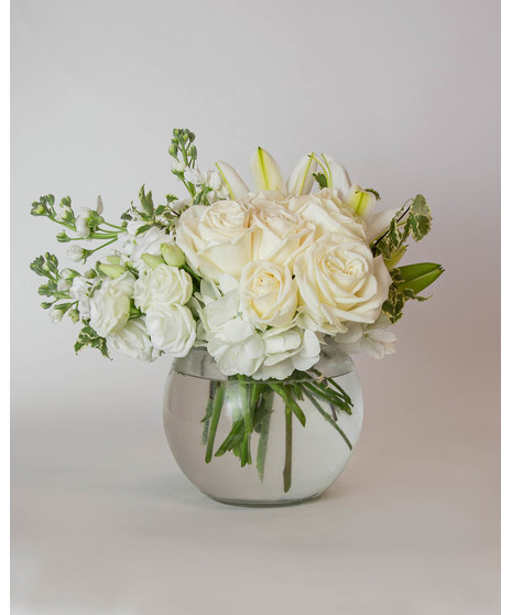 Beautiful roses are arranged in an elegant cylinder glass leaf-lined vase. 