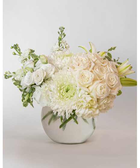 Beautiful roses are arranged in an elegant cylinder glass leaf-lined vase. 