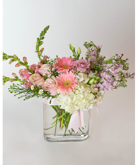 blush and ivory floral includes hydrangea, snapdragons, roses, lisianthus and more, designed in a contemporary thin glass vase and tied with a satin blush bow