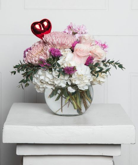 Sorbet Dream features peach, yellow, and orange roses in a leaf-lined vase.