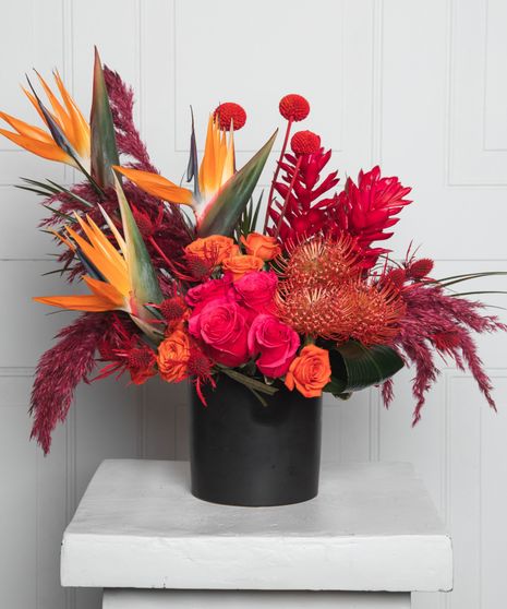 a luscious bouquet of locally grown sunflowers, hot pink and blush roses, colorful stock and snapdragons, lime green hydrangea, and more set in an elegant footed glass vase