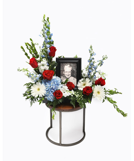Surround the photo of your loved one with red, white, and blue florals, the arrangement will bring comfort and peace to their family and friends during a time of loss.