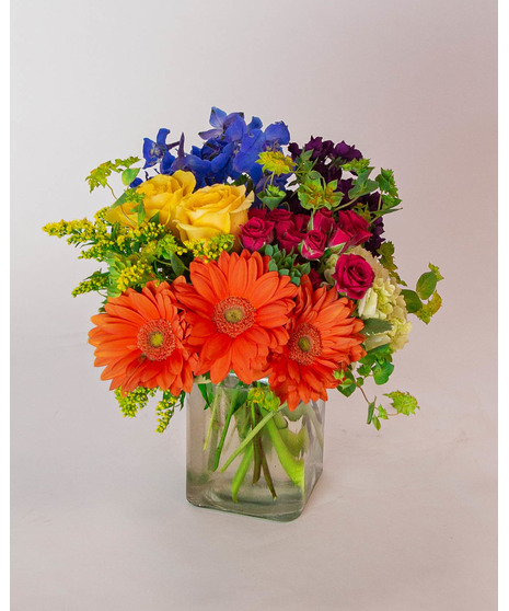 This colorful array of roses, gerbera daisies, delphinium, spray roses and more is sure to bring a smile to anyone's face.