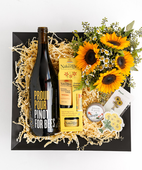 This gift box includes Pinot Noir, a fresh sunflower and chamomile arrangement, wildflower seeds, a Naked Bee Orange Blossom Honey pack, a floral pin, and sticker.