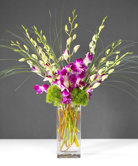 This arrangement includes stunning dendrobium orchids in a vase with exotic greenery.