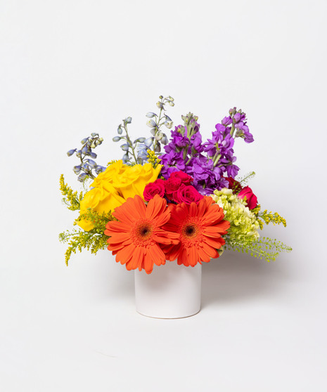This colorful array of roses, gerbera daisies, delphinium, spray roses and more is sure to bring a smile to anyone's face.