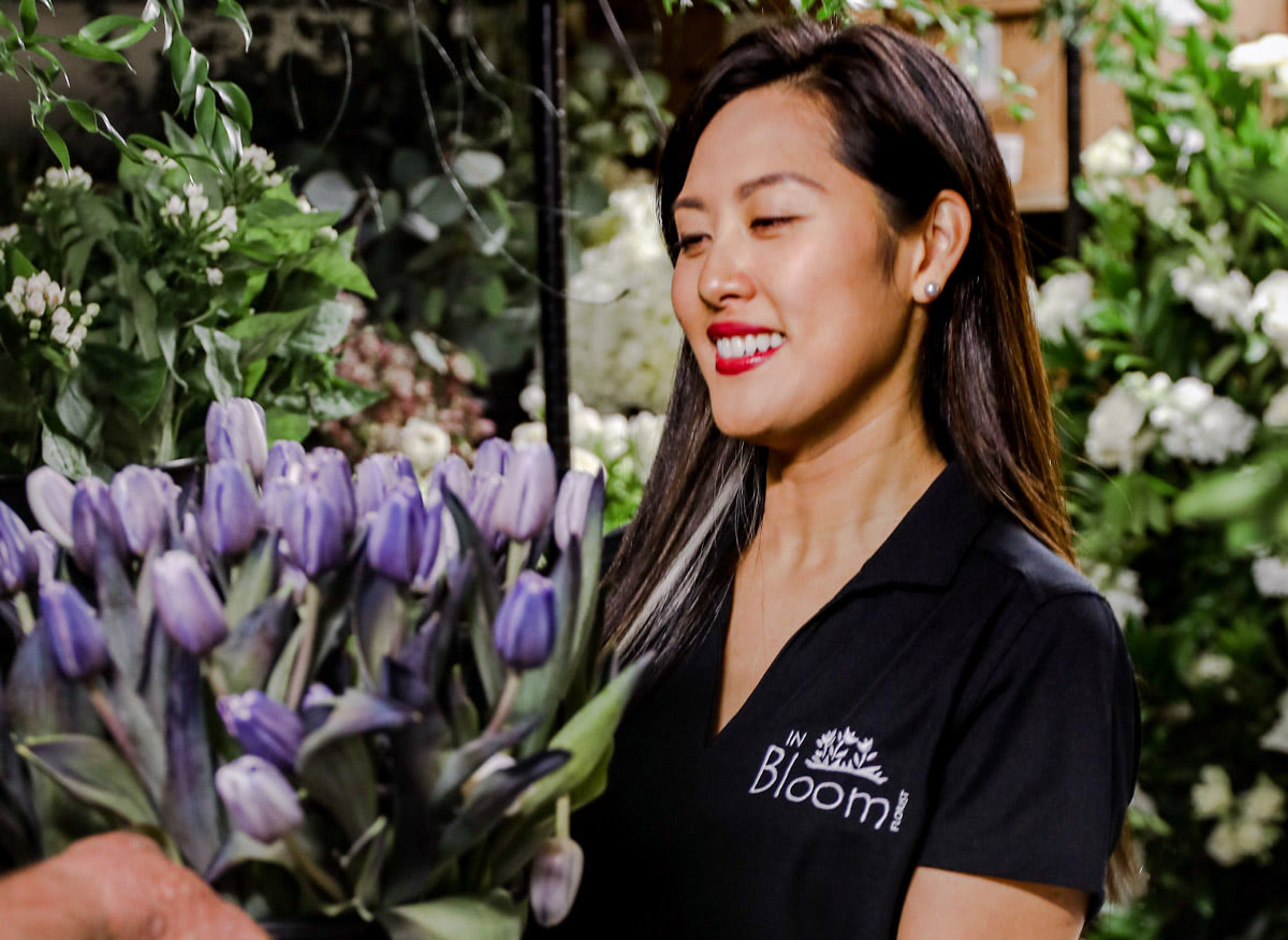 Susan Lo, In Bloom's owner, holds a large bucket of purple tulips
